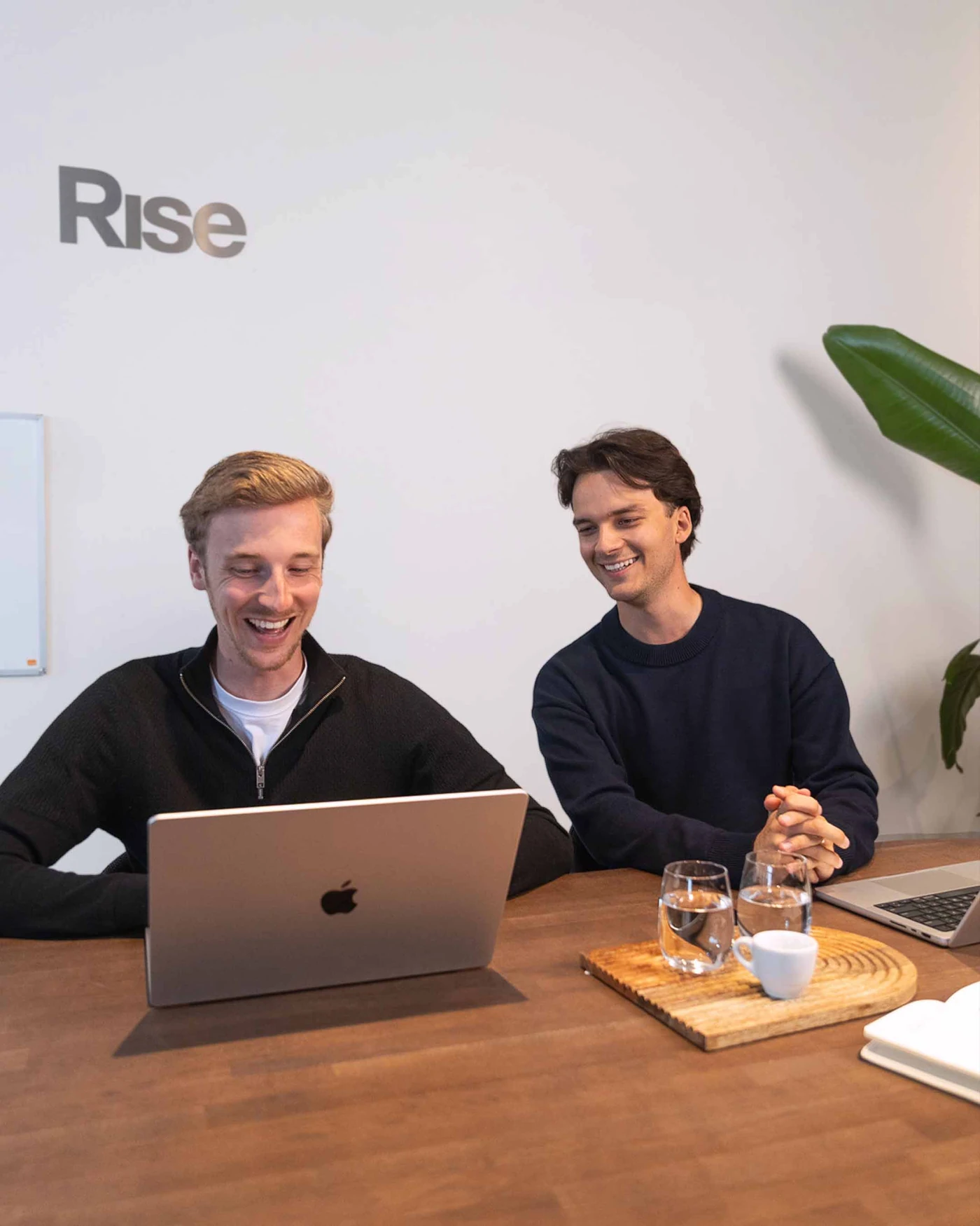 Twee collega's lachen bij een laptop